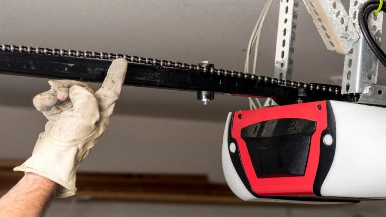 An offscreen technician tests the chain tension on a garage door opener.