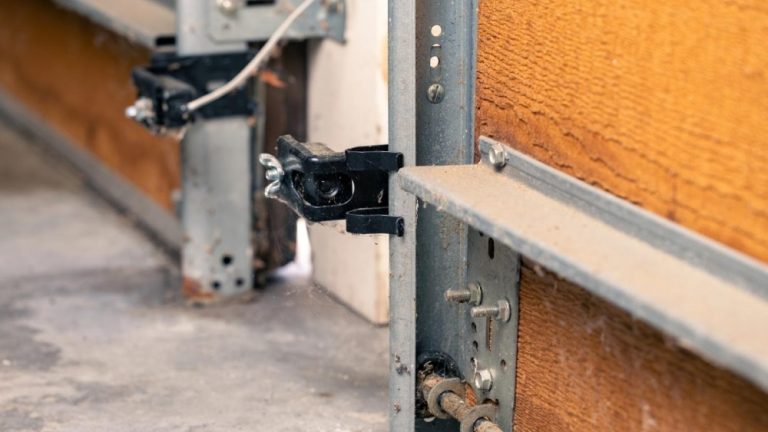 Close-up of the garage door safety sensor on the wooden door.