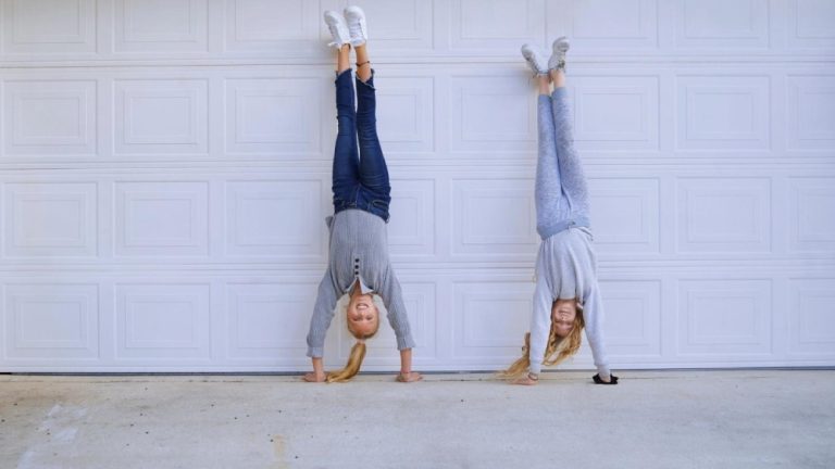 Girls doing a handstand in front of a garage door