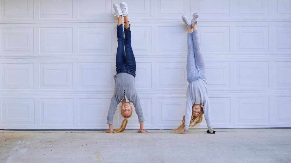 Girls doing a handstand in front of a garage door