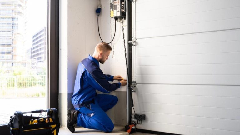 A professional technician is performing maintenance on a garage door.
